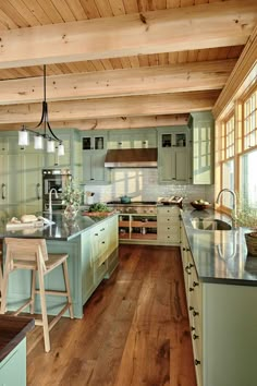 a large kitchen with wooden floors and green cabinetry on the walls, along with an island in the middle