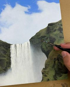 someone is painting a waterfall with water and clouds in the background, while holding a pair of scissors