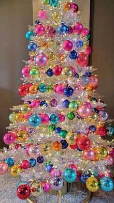 a brightly colored christmas tree with ornaments on it's base and lights in the shape of balls