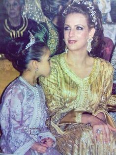 two women sitting next to each other wearing tiaras