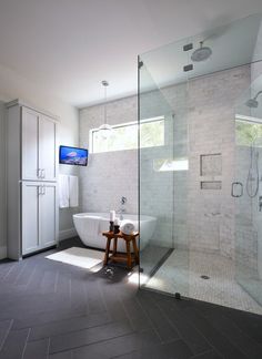 a large bathroom with a walk in shower next to a white tub and sink under a flat screen tv