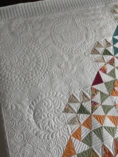 a close up of a quilt on a bed with many different colors and shapes in it