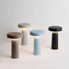 three different colored stools sitting next to each other on a white surface with light coming from the top