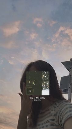 a woman is holding up her cell phone to take a selfie with the sky in the background