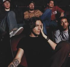 a group of men sitting next to each other in front of a movie theater seat