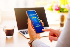 a person holding a cell phone in front of a laptop