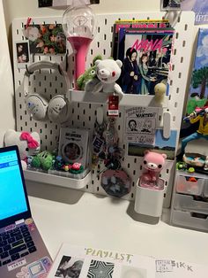 a laptop computer sitting on top of a desk next to a shelf filled with toys