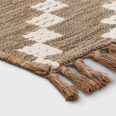 an area rug with tassels on the bottom and fringe at the end, in neutral colors