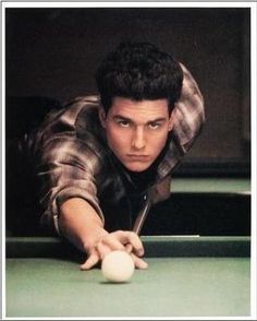 a man leaning over a pool table with a cue in his hand and looking at the camera