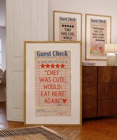 three framed posters on the wall in a room with wood floors and wooden furniture,