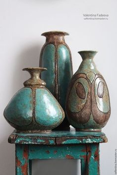 three vases sitting on top of an old wooden table next to each other in different colors