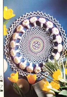 a crocheted doily with yellow flowers in the center on a blue wall