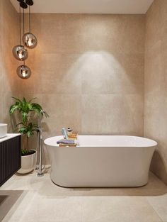 a white bath tub sitting in a bathroom next to a sink and mirror on the wall