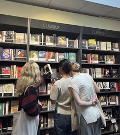 three women are looking at books in a book store