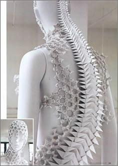 the back of a dress made out of white paper with spikes and chains on it