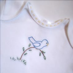 a white shirt with a blue bird embroidered on it