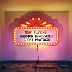 a neon sign that says now playing mission impossible ghost photocool on the wall