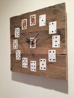 a clock made out of playing cards on a wooden wall mounted to the side of a wall