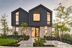 a modern house with landscaping and trees in the front yard