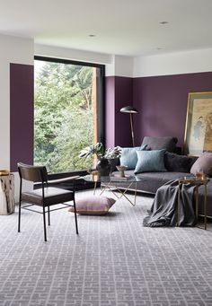 a living room filled with furniture and a large window covered in purple paint on the walls