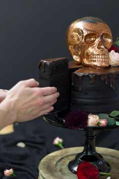 a person is decorating a cake with flowers and skulls on the top, while holding a camera