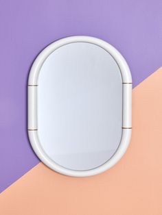 a round mirror mounted to the side of a wall next to a purple and pink wall