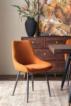 two orange chairs sitting next to each other in front of a painting