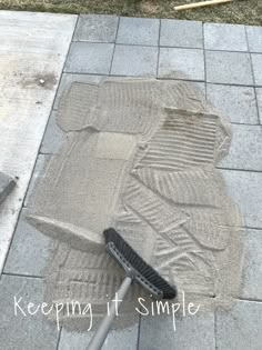 a broom is laying on the ground next to a sidewalk that has been covered with sand