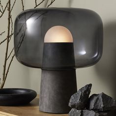 a black lamp sitting on top of a wooden table next to rocks and a vase