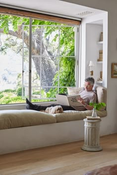 a man sitting on a window sill using a laptop computer