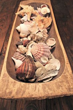 a wooden bowl filled with seashells on top of a table