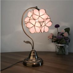 a lamp that is sitting on top of a table next to a vase with flowers