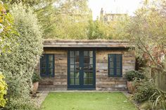 a small wooden building sitting in the middle of a lush green yard