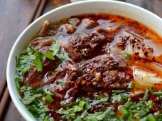 a bowl filled with meat and vegetables on top of a wooden table