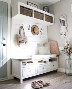 a white bench with baskets and flowers on it next to a wall mounted coat rack