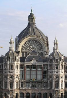 an ornate building with many windows and clocks on it's front side, surrounded by other buildings