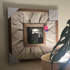 a potted plant sitting next to a wooden frame with an intricate design on it