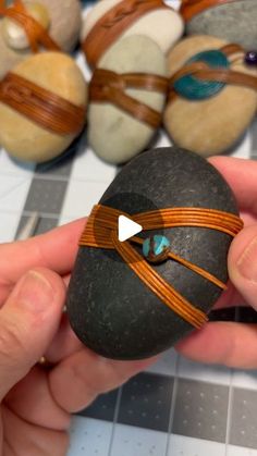 a person holding an object in their hand with other rocks and stones behind it on the table