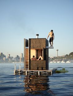 a man standing on top of a floating structure in the water next to another person