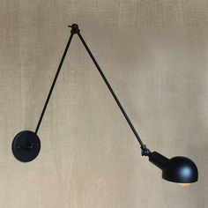 a black wall light hanging from the side of a wall with a cord attached to it