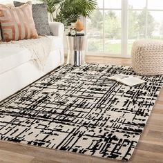 a living room with a white couch and black and white rug