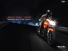 a man riding on the back of an orange motorcycle at high speeds in the dark