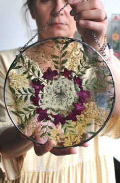 a woman holding up a glass plate with flowers on it and chains around her neck