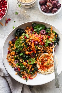 a white bowl filled with salad next to bowls of olives and cranberries