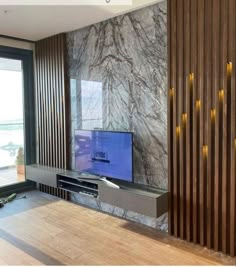 a flat screen tv sitting on top of a wooden shelf in a living room next to a window