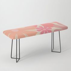 a pink and white floral bench with black metal legs on an isolated grey background,