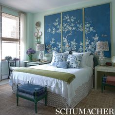 a bedroom decorated in blue and green with flowers on the wall above the headboard