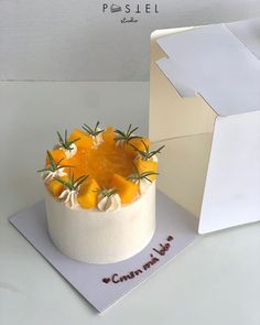 a cake with oranges and rosemary on top is displayed in front of an open box