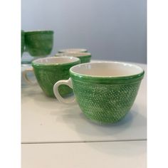 three green cups sitting next to each other on a table