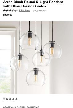 five clear glass globe pendant lights hanging from a ceiling fixture in a room with white walls and windows